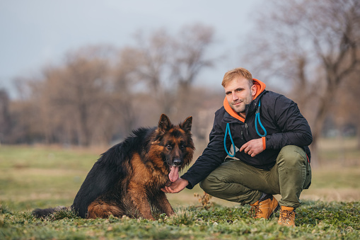 Young man and German shepherd in park