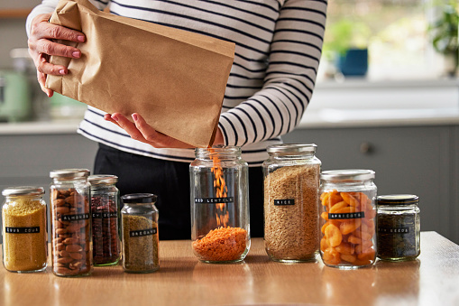 Mujer ahorrando en envases llenando frascos reciclados para almacenar alimentos secos en casa photo