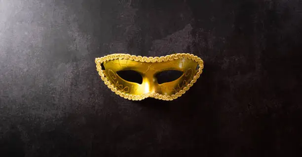 Happy Purim carnival decoration concept made from golden mask on dark background. (Happy Purim in Hebrew, jewish holiday celebrate)