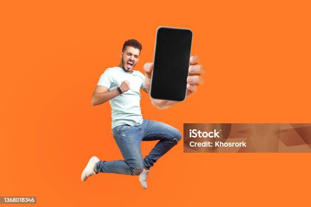 Happy Man Flying And Jumping In Air And Showing Big Mobile Empty Screen Stock Photo - Download Image Now