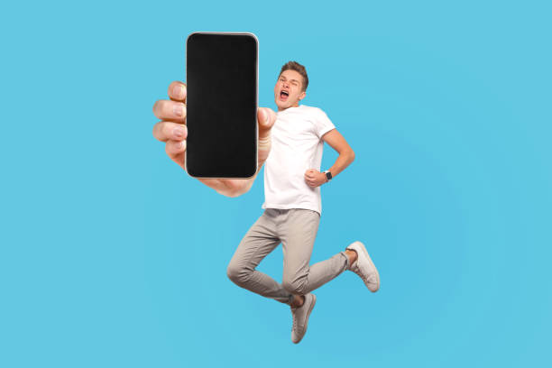 istock Happy man flying and jumping in air and showing big mobile empty screen 1368018358