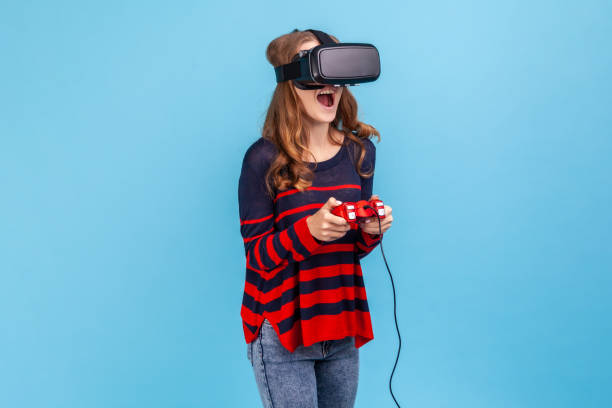 istock Woman in vr headset, playing virtual reality game with joypad, has excited smile on her face. 1368019041