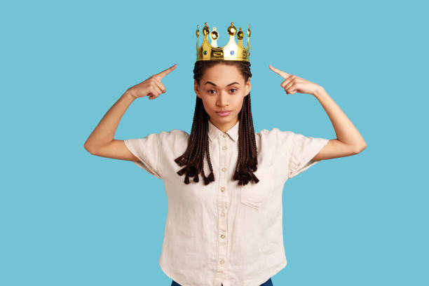 istock Woman with dreadlocks points at gold crown, looking with arrogance and confidence, privileged status 1368019314