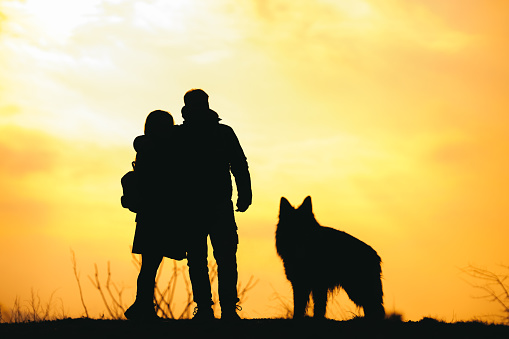 A loving couple in a park with a German shepherd. Siuleta.