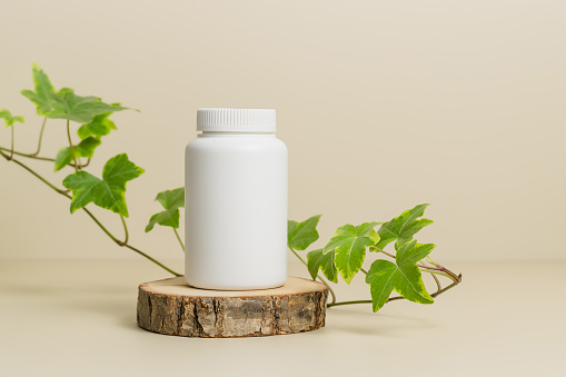 Medical mockup bottle for pills or vitamins with ivy plant leaves at the background, bio supplement, eco friendly, healthy lifestyle