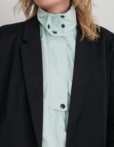 Woman is wearing a black classic jacket over a turquoise sports jacket.