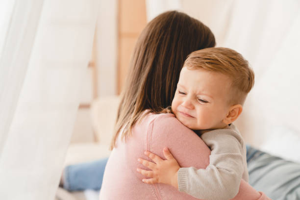 mãe caucasiana embalando seu filho pequeno chorando filha bebê recém-nascido. cólicas, problemas de saúde. depressão pós-parto. maternidade e cuidado com a criança - diarreia - fotografias e filmes do acervo