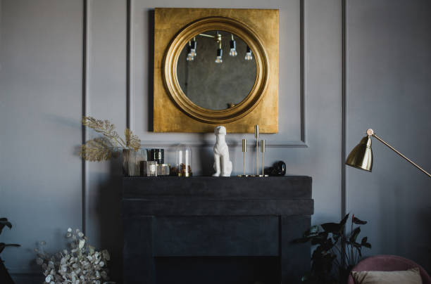 istock Modern interior with big mirror in golden frame hanging above black decorative fireplace. 1368024342