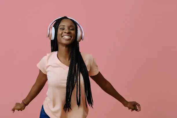 Beautiful young woman dancing and listening music in headphones