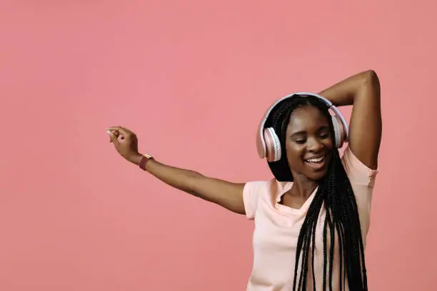 Beautiful young woman dancing and listening music in headphones
