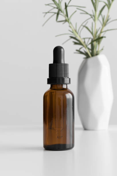 Dropper bottle mockup with a rosemary on the white table.