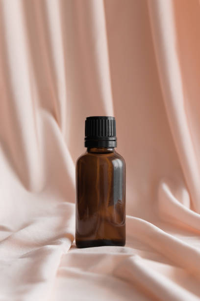 istock Amber glass essential oil bottle mockup on the soft pink textile. 1368024802