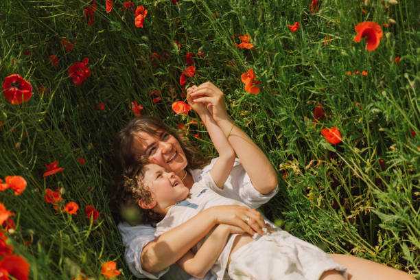 feliz día de la madre. niño y madre está jugando en un hermoso campo de amapolas rojas. - poppy field fotos fotografías e imágenes de stock