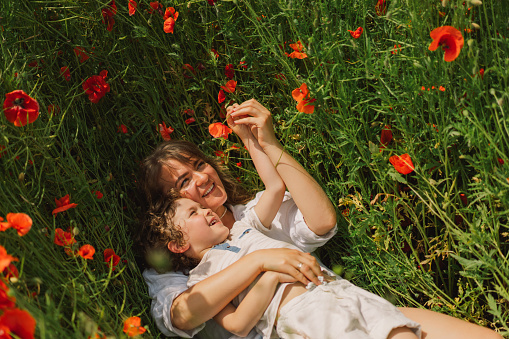 Happy Mother's Day. Little boy and mother is playing in a beautiful field of red poppies. People and nature. Rural scene