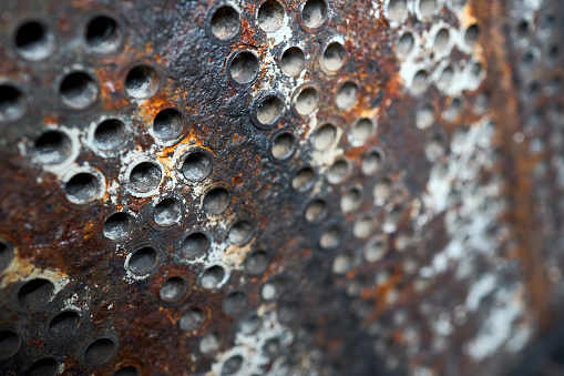 Tube sheet or plate of heat exchanger boiler closeup texture selective focus background opened for inspection maintenance or cleaning from insoluble hard mineral deposits, salts scale and corrosion.