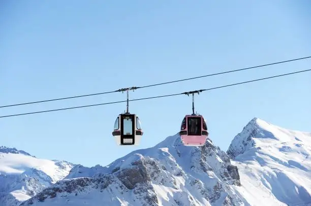 Vintage gondolas in ski resort  over snowcapped mountains