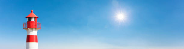 istock Lighthouse in front of a blue sky with sun 1368032667