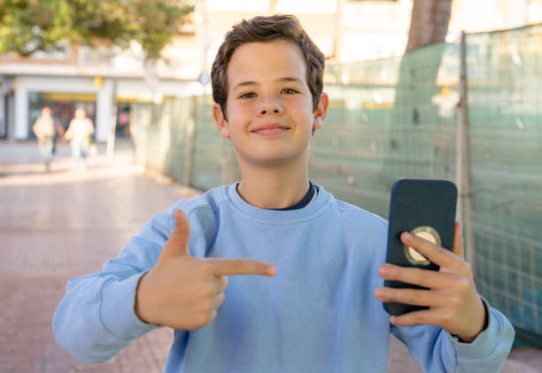 istock Smiling cute boy with smartphone standing outdoors. 1368033320