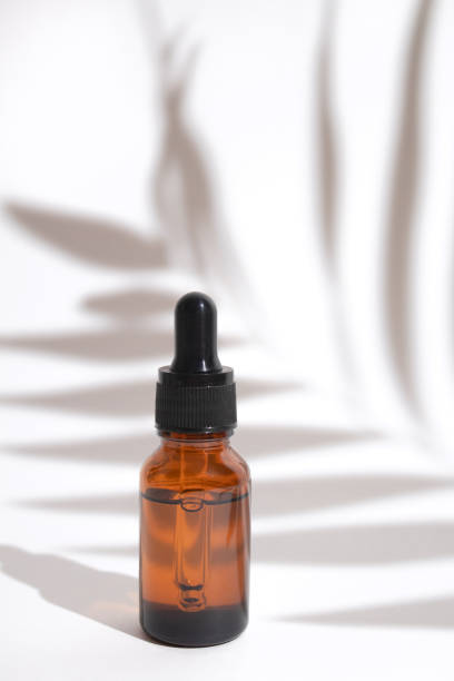 istock Glass dropper bottle with shadow palm leaves. Cosmetic container mock-up. Creative minimalistic shot of a cosmetic product. Spa concept. Mock-up bottle for branding and label 1368033327