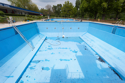 Drained swimming pool. Cleaning equipment, preparing for the summer season