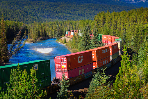 Banff National Park, Canada - September 21, 2021 : Freight train passing through the Morant's Curve in bow valley with Rocky Mountains in the background.