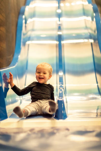 Kid riding from childrens slides in game center stock photo