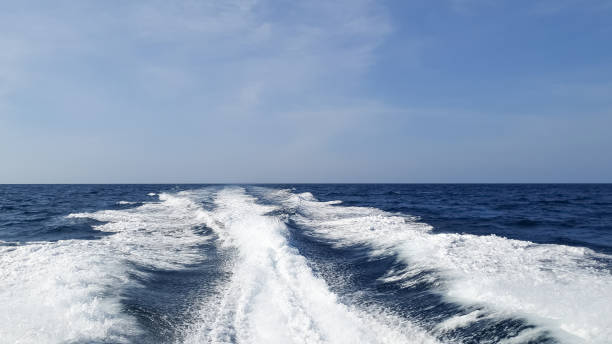 istock Sea wake trail behind a speed boat with waves, foam, bubbles on the ocean water surface with clear bright blue sky. Travel in summer season. Trail on water surface behind of fast moving motor boat. 1368037191