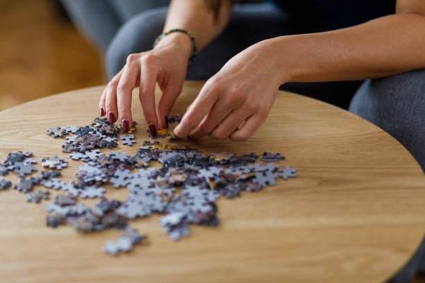 istock Woman solving a jigsaw puzzle on a wooden coffee table 1368037227