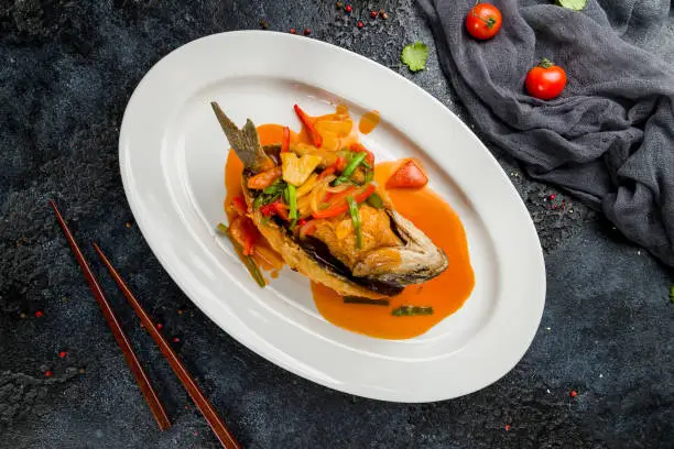fish fillet in sweet and sour sauce on dark stone table