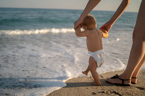 Mother and baby feet walking on sand beach