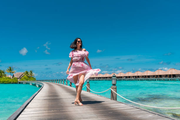 istock Beautiful woman walking on jetty bridge in Maldives 1368042425