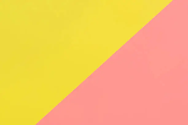Abstract minimalist background with paper texture in pastel pink and yellow tones. Background divided equally diagonally