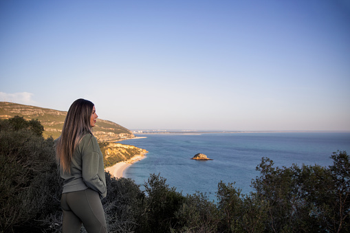 Woman appreciating the amazing view at Serra da Arrábida of Portinho da Arrábida, in Sesimbra, Portugal