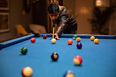 young man playing billiard game ( pool game ) at indoor club