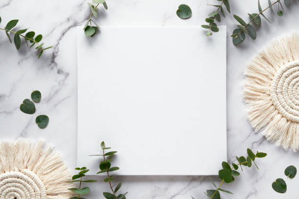 istock Mockup with blank square canvas, copy-space. Fresh eucalyptus twigs. Top view on white marble table 1368045180