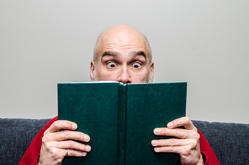 Close up on man reading a book
He makes a surprised facial expression