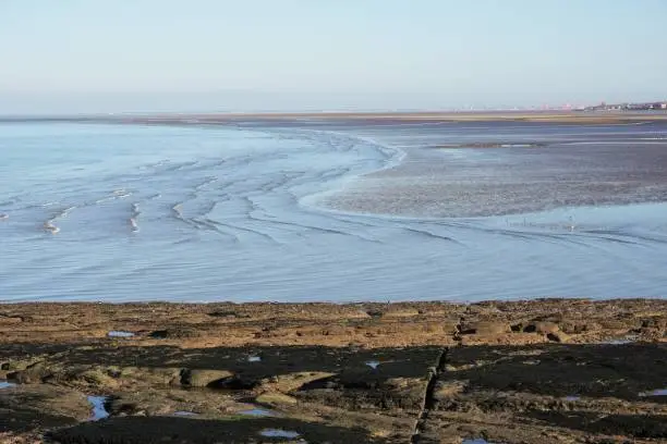 Hilbre Island. Wirral, England - 13 January 2022: Looking down on the Dee Estuary close to low tide. On the right hand horizon houses in Hoylake, and further back red cranes of Liverpool docks are visible.