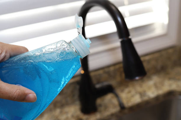 접시 세제 한 병을 손에 들고 있는 한 여성 - dishwashing detergent 뉴스 사진 이미지