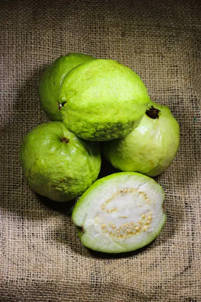 Heap of green guava and its slice on a jute texture background.Close up guava fruit.