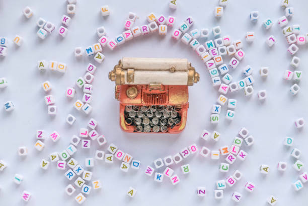Alphabet beads with miniature typewriter on white background.