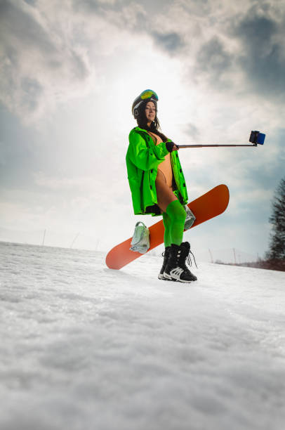 istock Beautiful woman using smartphone to making selfie with a snowboard on a ski slope 1368047085