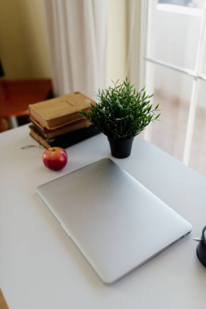 istock Closed laptop, apple, flowers and old bookd on the table. 1368049121