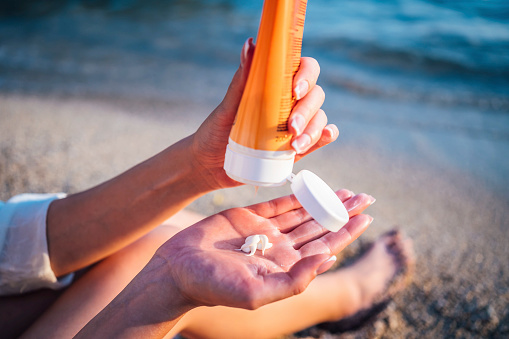 Woman using sunscreen cream on the beach