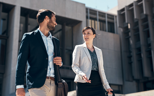 Low angle view of successful Miami businessman in mid 30s wearing suit and looking up with a smile as he stands outdoors in downtown district.