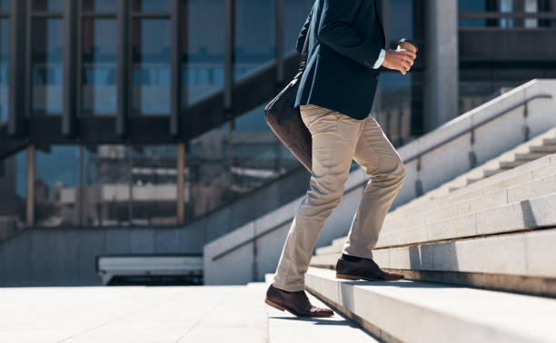 Shot of a businessman walking up a flight of stairs against an urban background Every step brings you closer to success steps and staircases stock pictures, royalty-free photos & images