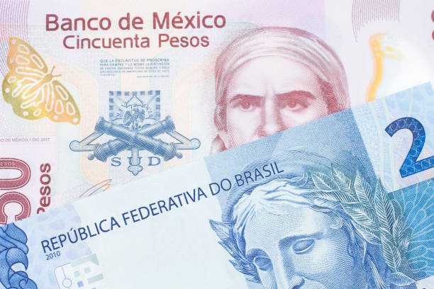 A pink, plastic fifty peso bank note from Mexico paired with a blue two real bank note from Brazil. stock photo