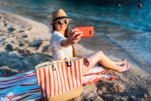 Young cheerful woman taking selfie on the beach