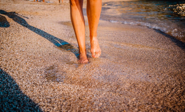 istock Female feet step on the sea wave 1368050309