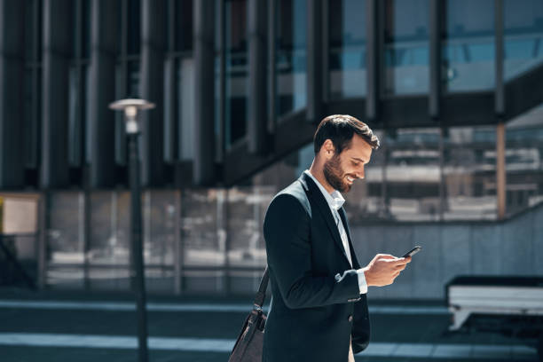 Shot of a young businessman using a smartphone against an urban background stock photo