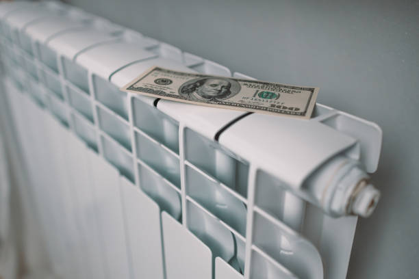 istock Paying bills. Dollar money banknotes on heating radiator battery at home. Expensive heating costs. 1368053656